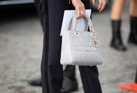 Luxury Clothing - person in black pants holding white leather handbag