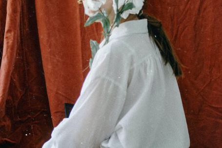 Supreme's Allure - Side view of unrecognizable young female in elegant clothes sitting in vintage studio and covering face with bunch of delicate white flowers