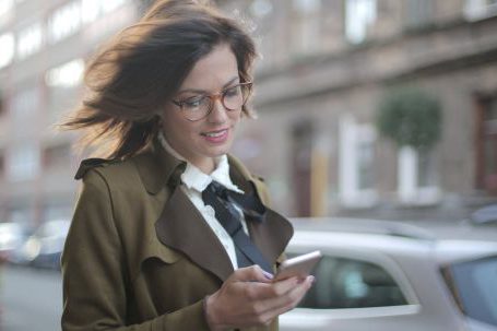 Mobile Shopping Guide - Stylish adult female using smartphone on street