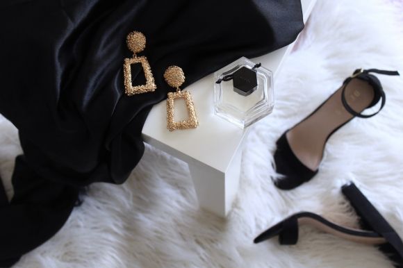 Luxury Clothing - pair of gold-colored earrings on table and black ankle-strap pumps on area rug